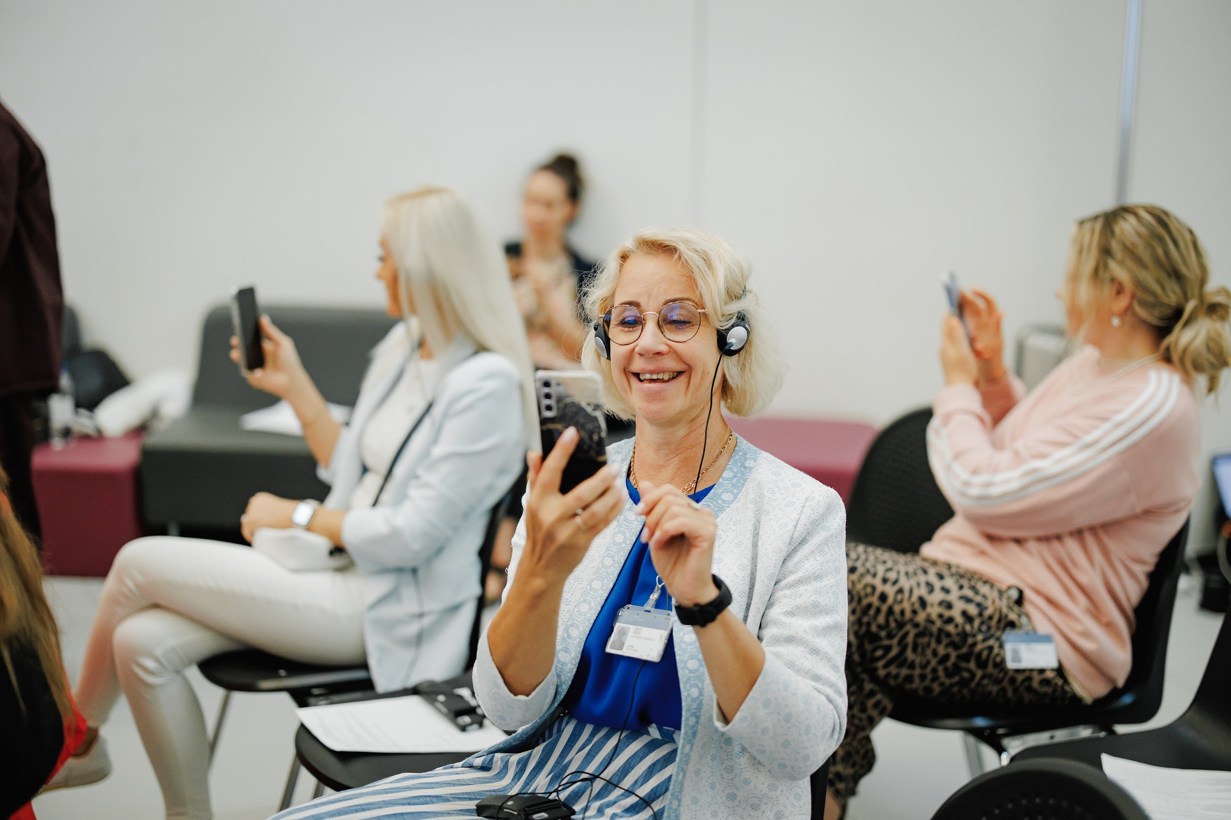 Woman smiling while looking at her phone at a conference.