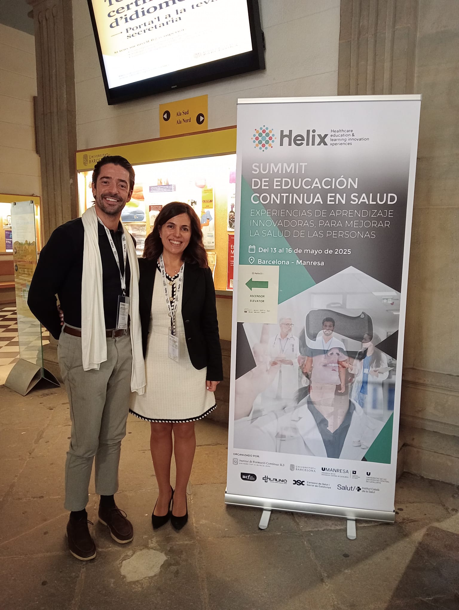 Two people in front of a roll up poster.
